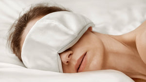 Resting woman wearing the OPSUNDBAY Deepsilk Sleeping Mask, enjoying uninterrupted sleep. Made from soft 25 momme Mulberry silk, the mask features a comfortable fit, providing complete darkness while being gentle on the skin, ensuring a deep and restful REM sleep.